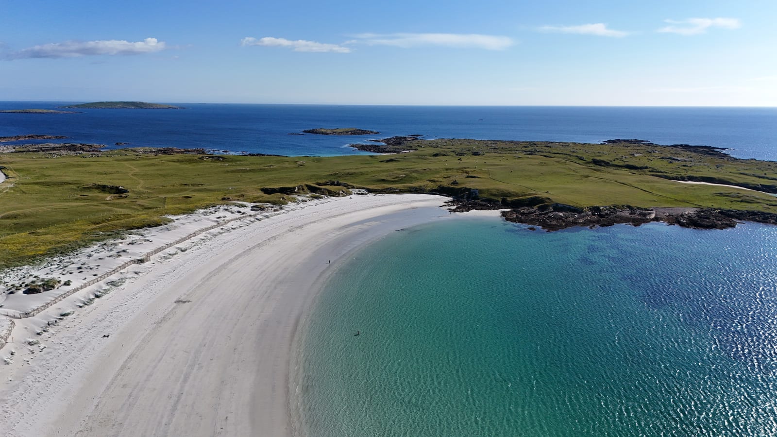 Aerial view of a curved white-sand beach and turquoise bay in the west of Ireland