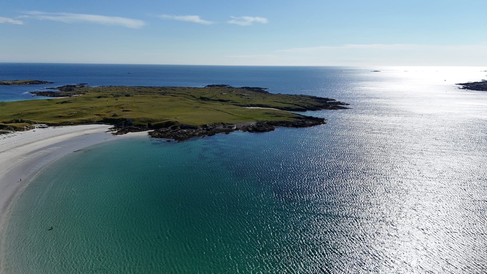 Aerial view of a sunlit headland and offshore islands